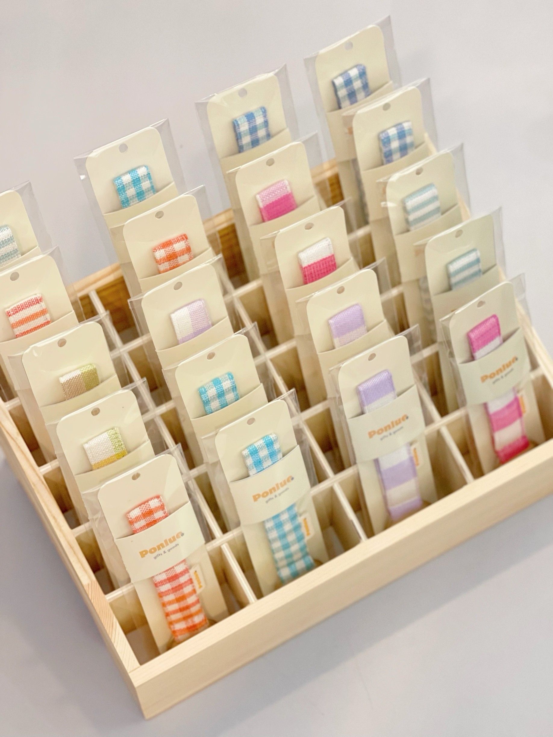 Ponlue Kroma keychains arranged in a wooden display tray from an angle