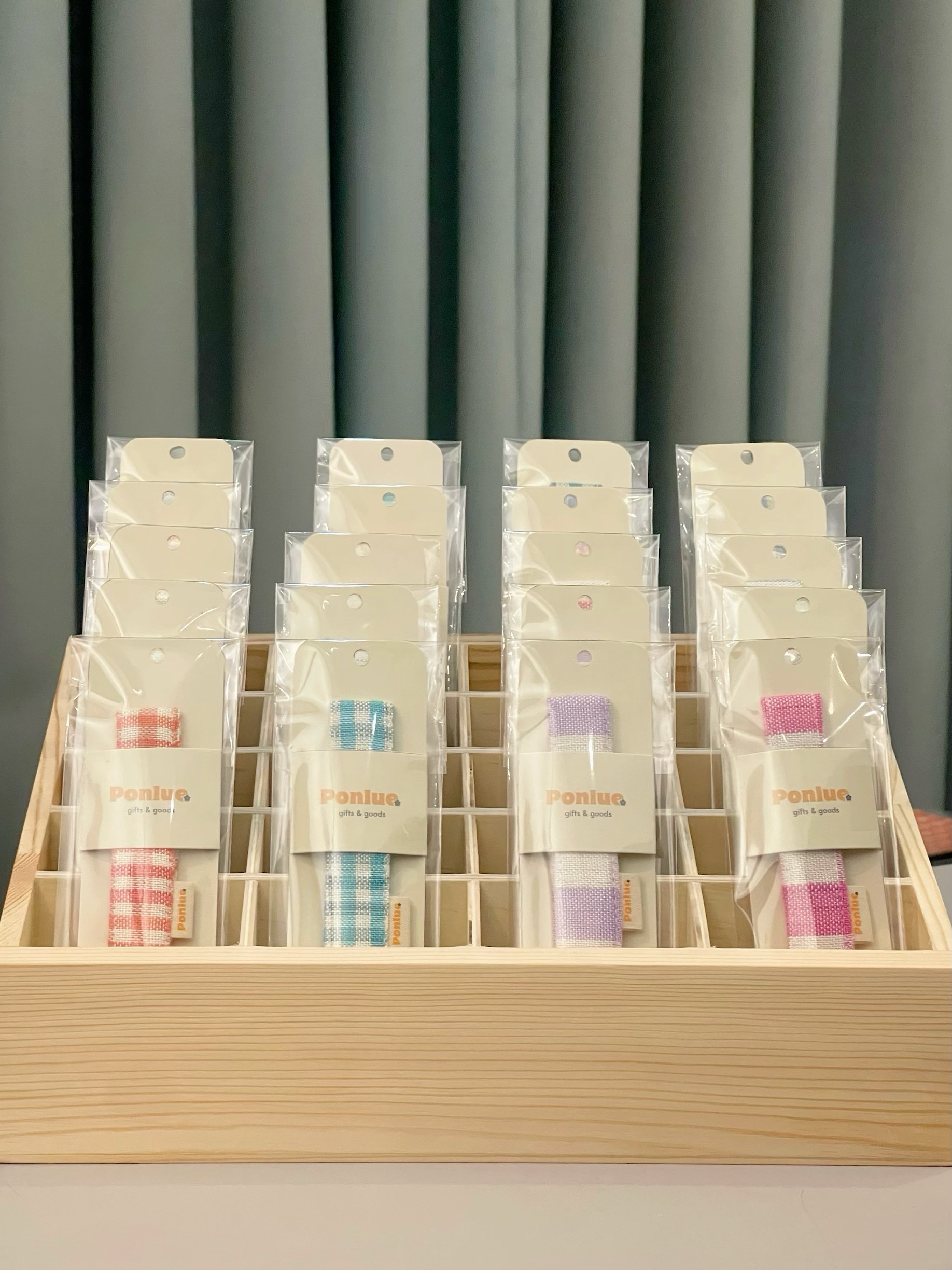 Ponlue Kroma keychains displayed in a wooden retail tray