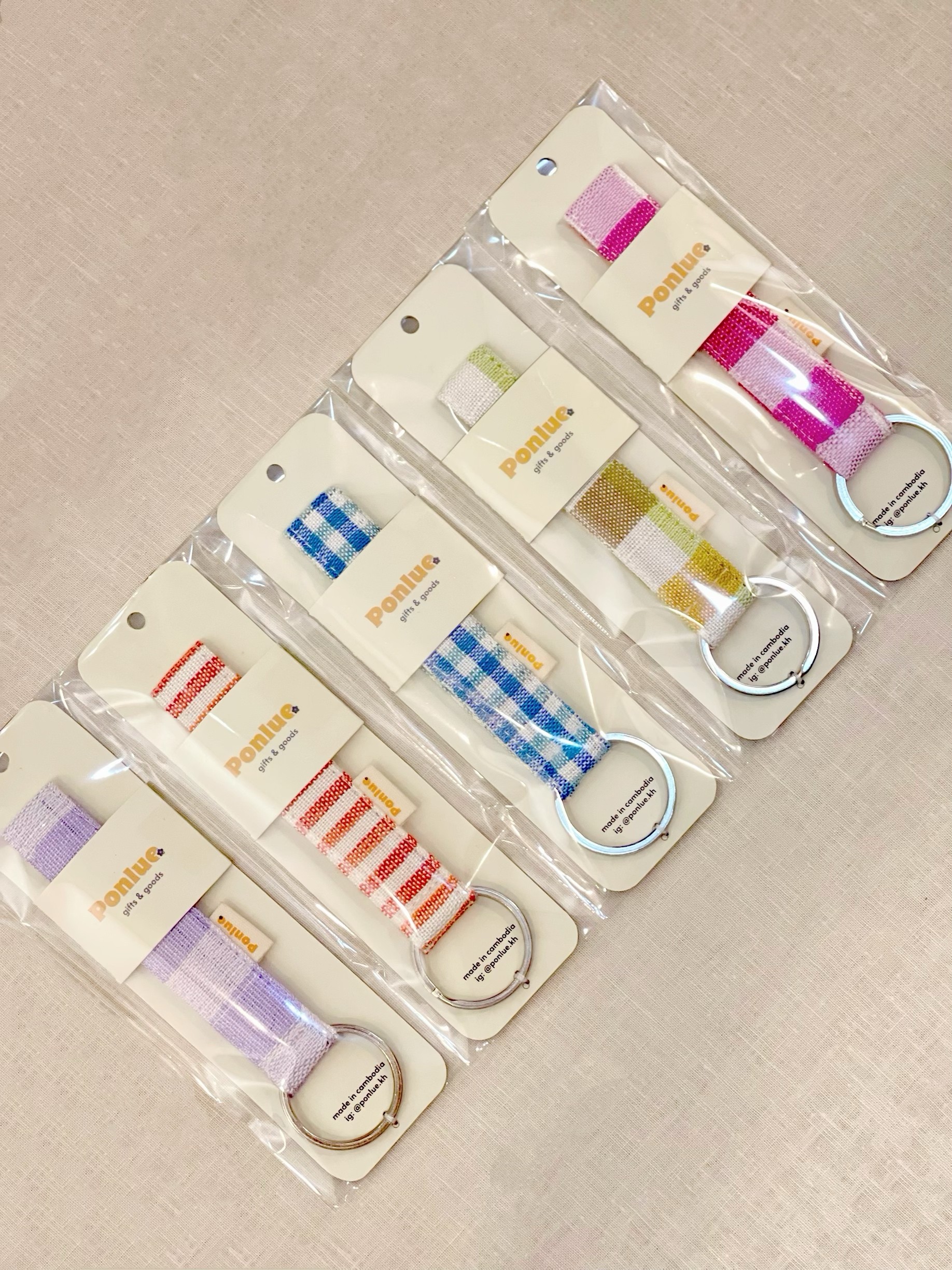 Ponlue Kroma keychains packaged in multiple colors on a fabric surface